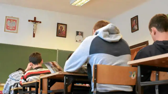 Uczniowie siedzą w klasie z portretem papieża i krzyżem na ścianie. Czy religia wlicza się do średniej?
