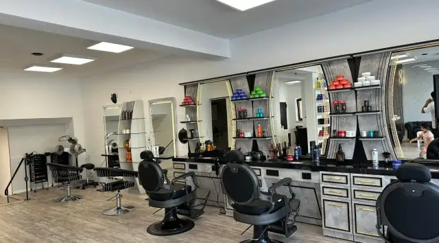 Friseurstuhl und Spiegel in einem modernen Salon mit Regalen voller Kosmetikprodukte.