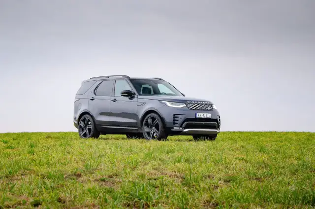 Szary Land Rover Discovery stoi na zielonej łące.