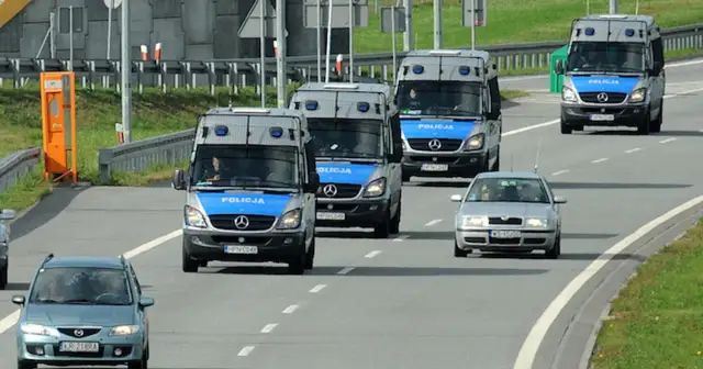 Konwój pojazdów uprzywilejowanych: policyjne furgonetki i samochód osobowy jadące autostradą.