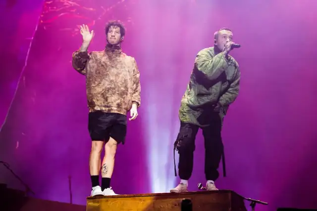 Tyler Joseph i Josh Dun z twenty one pilots na koncercie. Jeden wita publiczność, drugi śpiewa.