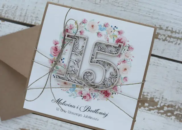 Elegancka kartka z napisem "15 rocznica ślubu" dla Malwiny i Bartłomieja, ozdobiona kwiatowym wianuszkiem i przewiązana sznurkiem.