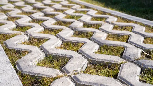 Podjazd z płyt ażurowych, przez które przebija się zielona trawa. Idealne rozwiązanie dla ekologicznego podjazdu.