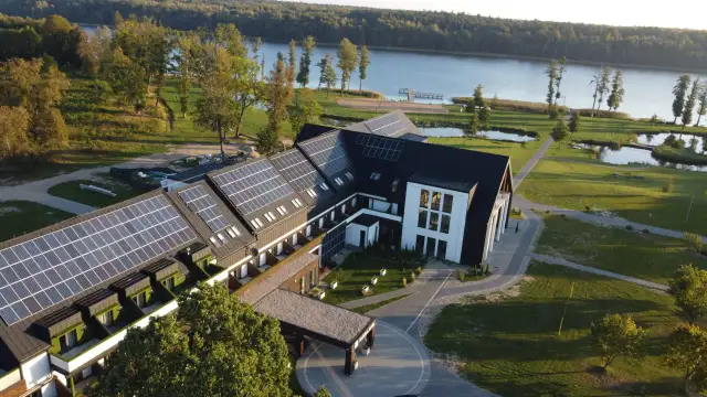 Nowoczesny hotel z panelami słonecznymi nad jeziorem, idealny na Mazury all inclusive.