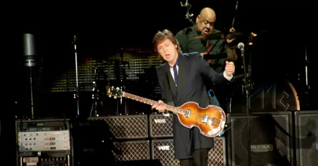 Paul McCartney na jednym ze swoich koncertów, grając na gitarze basowej. W tle perkusista.