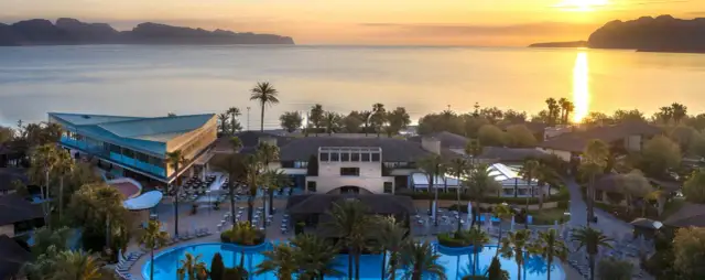 Resortanlage mit Pool und Meerblick bei Sonnenuntergang.