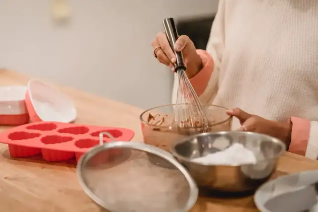 Przygotowania do pieczenia muffinek w silikonowych foremkach. Mieszanie masy w misce trzepaczką.