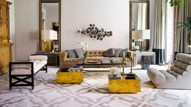 Sofá de terciopelo marrón, mesas doradas y alfombra geométrica crean una acogedora **conversation pit**.