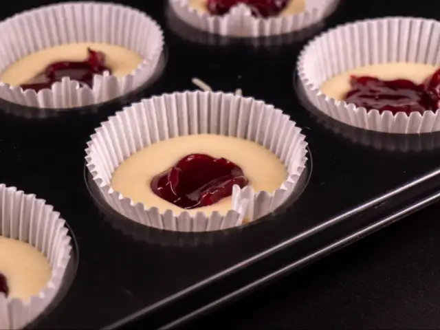 Nadziewane dżemem muffinki w papierowych foremkach w blaszce.