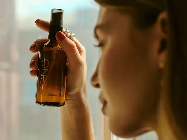 Kobieta trzyma buteleczkę z mgiełką. Czy cetearyl alcohol to składnik tej mgiełki?