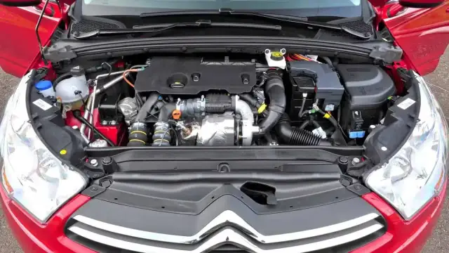 Silnik w czerwonym Citroen C4 2008. Widok komory silnika z turbosprężarką i przewodami.