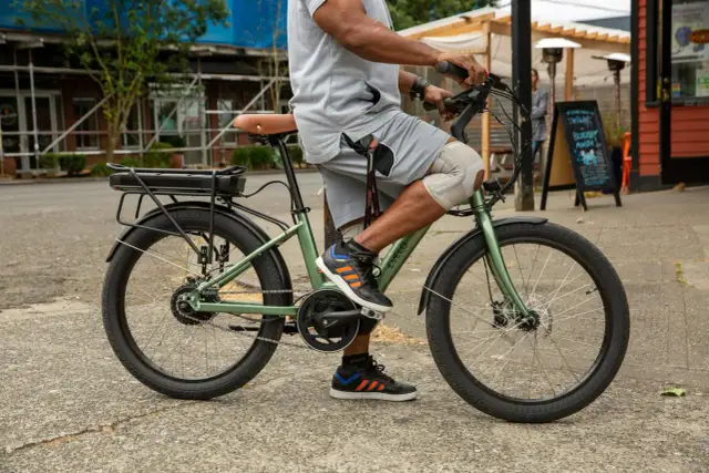 Mężczyzna na zielonym rowerze elektrycznym, idealnym do miejskich podróży. Ten model z pewnością znalazłby się w czołówce rankingu rowerów elektrycznych.