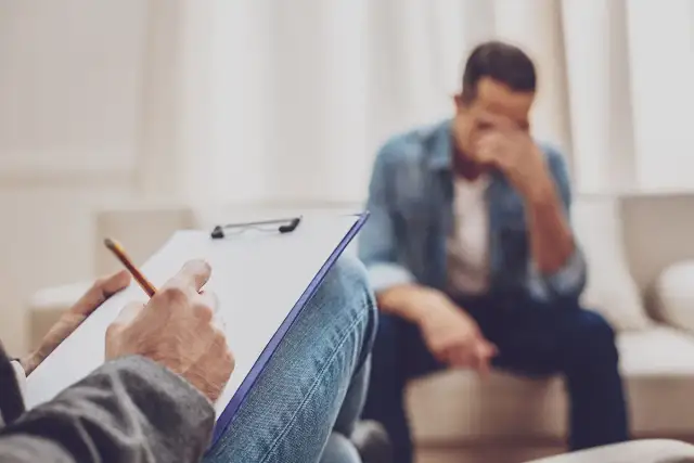 Terapeuta notuje podczas rozmowy z mężczyzną w depresji.