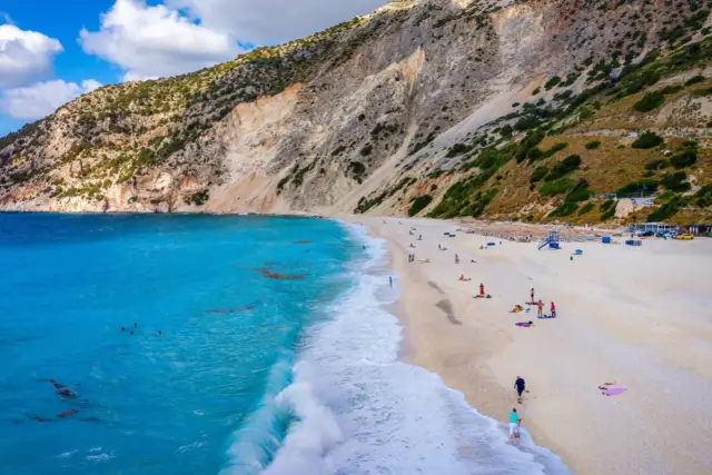Widok z lotu ptaka na plażę Myrtos na Kefalonii z turkusową wodą i stromym klifem.