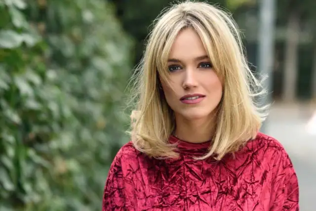 Blondynka w czerwonej, aksamitnej bluzce z modnym clavi cut.