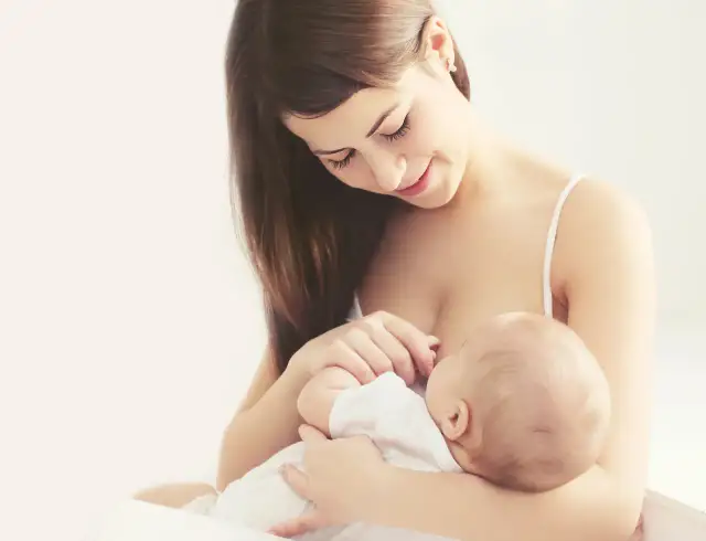 Uśmiechnięta mama karmi piersią dziecko, moment kiedy stabilizacja laktacji przynosi spokój i bliskość.