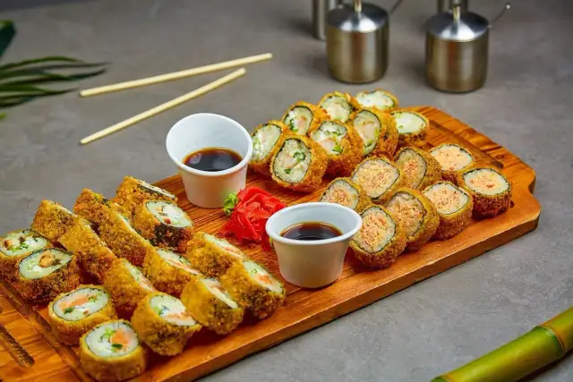 Talerz z różnymi rodzajami smażonych rolek sushi, sos sojowy i marynowany imbir.