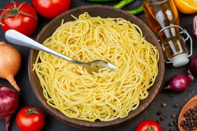 Porcja makaronu spaghetti w drewnianej misce, gotowa do podania. Trudno określić, ile cm ma makaron spaghetti, ale wygląda na idealnie ugotowany.