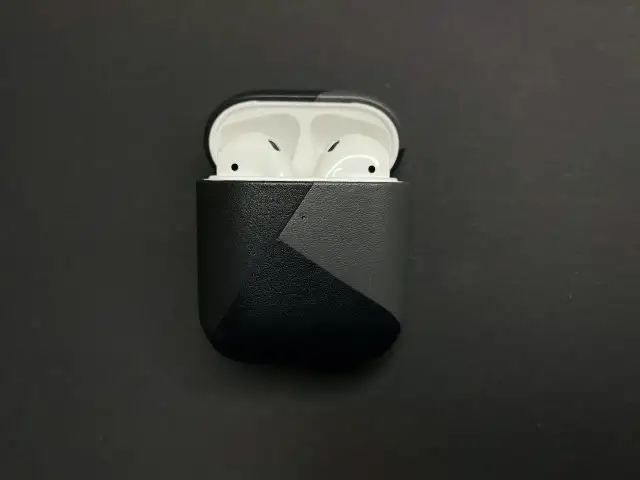 AirPods in einer schwarzen Hülle mit grauem geometrischem Muster.
