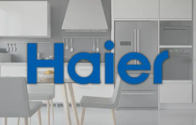 Nowoczesna kuchnia z lodówką i piekarnikiem. Duży napis "Haier" informuje, haier co to za firma, znana z produkcji sprzętu AGD.