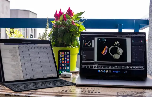 iPad Pro mit Tastatur, iPhone, AirPods und MacBook Pro mit Kopfhörern und Schlüsseln.