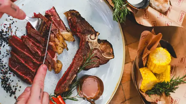 Idealne jakie wino do wołowiny? Soczysty stek T-bone z pieczonymi ziemniakami i kukurydzą.