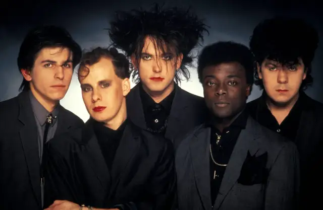 The Cure w pełnym składzie, z charakterystycznym makijażem i fryzurami, prezentują swoje kultowe utwory.