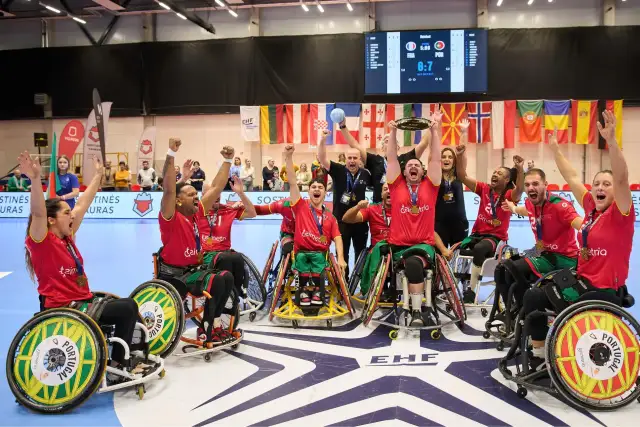 Drużyna Portugalii w piłce ręcznej na wózkach świętuje zwycięstwo. Na ekranie wynik meczu, a w tle flagi państwowe i logo EHF.