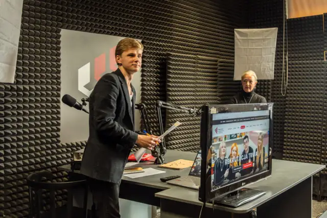 Młody mężczyzna z dokumentami w ręku i starsza kobieta w studiu radiowym. Rozmawiają o tym, czy po technikum można iść na studia.