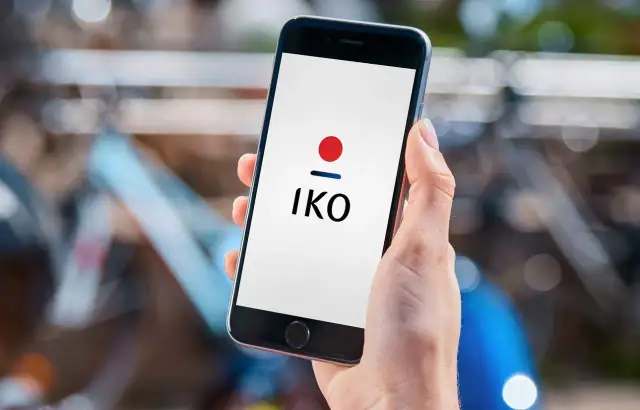 Dłoń trzyma smartfon z logo IKO. Dowiedz się, jak założyć IKO w telefonie, by wygodnie płacić.