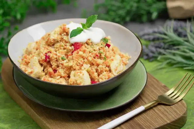Schüssel mit Hähnchen und buntem Gemüse, garniert mit Joghurt und Minze. Ein köstliches Gericht, das zeigt, dass ist Couscous low carb möglich ist.