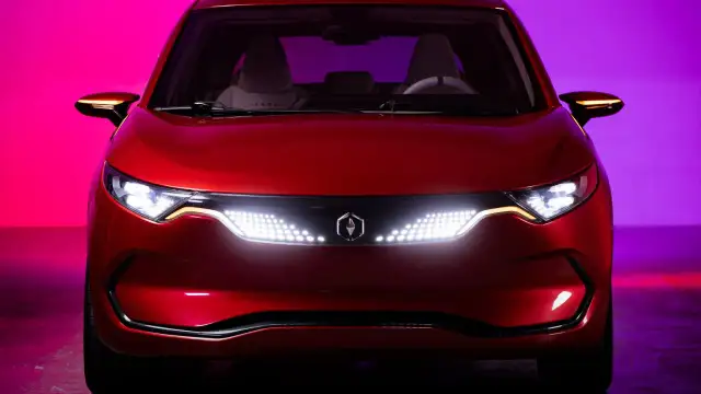 Czerwone izera auto z nowoczesnymi światłami LED i logo producenta na tle fioletowo-różowego oświetlenia.