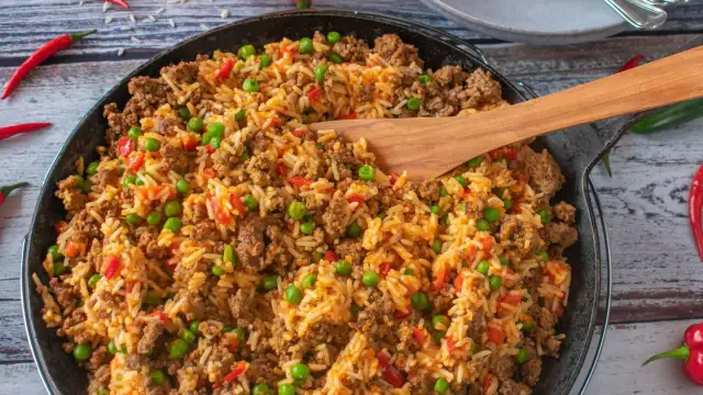 Herzhafte hackfleisch reis pfanne mit Erbsen und Paprika, garniert mit Chilischoten. Ein köstliches Gericht für die ganze Familie.