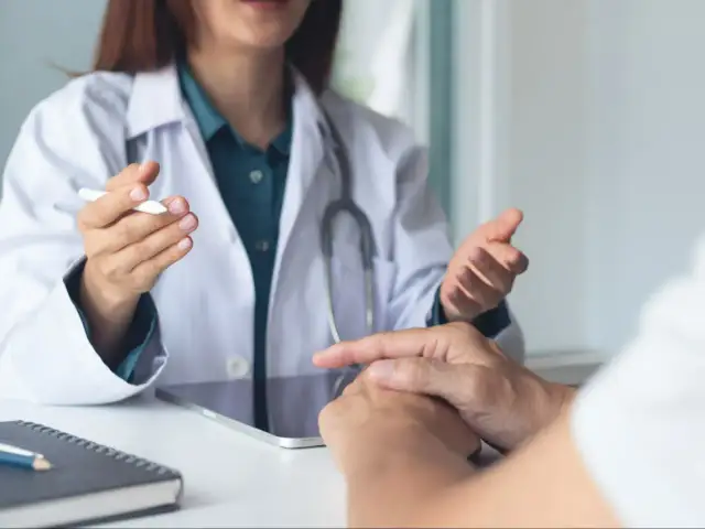 Lekarz w białym kitlu rozmawia z pacjentem, omawiając jego stan. Pytanie, czy rehabilitant może wystawić L4, jest kluczowe dla wielu osób.