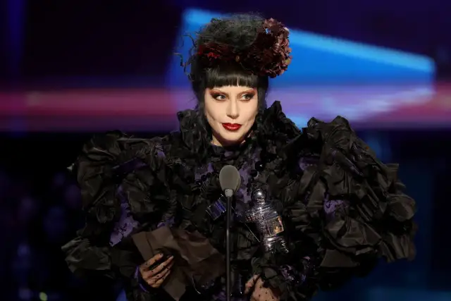 Lady Gaga w Polsce, w czarnej, falbaniastej sukni z fioletowymi wstawkami, odbiera nagrodę.