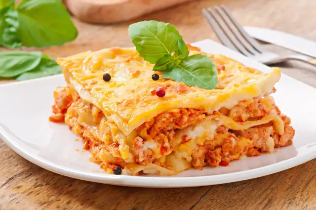 Pyszna lasagne z mięsem i serem, ozdobiona bazylią i pieprzem. Idealna na obiad, czy to lasagne czy cannelloni, smakuje wybornie.