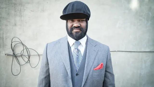 Gregory Porter w eleganckim garniturze i czapce, gotowy na koncert.
