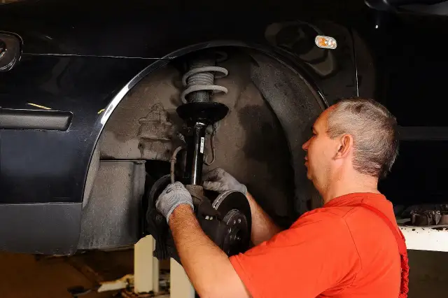 Mechanik naprawia zawieszenie, by auto nie ściągało w lewo podczas jazdy.