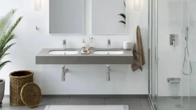 Nowoczesna łazienka z podwójną umywalką nablatową, montaż umywalki z szafką podwieszaną, prysznic walk-in i wiklinowy kosz.