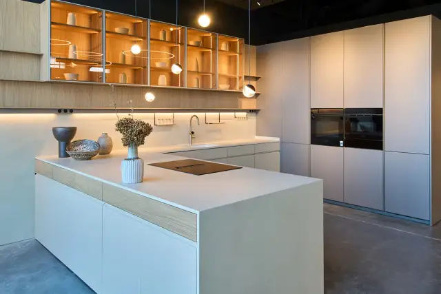 Cocina moderna con isla central, gabinetes de madera y acero inoxidable, y hornos integrados. Diseños cocinas minimalistas y elegantes.