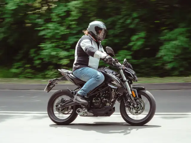 Mężczyzna w kasku jedzie czarnym motocyklem, który może być najmocniejszym motocyklem na kat B.