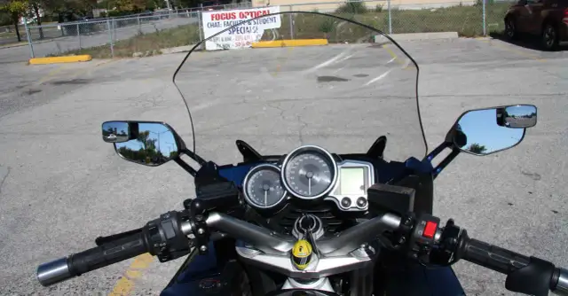 Widok z motocykla: przedłużenie lusterek motocyklowych, deska rozdzielcza z prędkościomierzem i obrotomierzem.