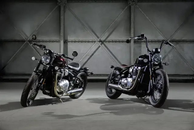 Dwa motocykle Triumph Bonneville Bobber w ciemnych kolorach, stojące obok siebie w industrialnym wnętrzu.