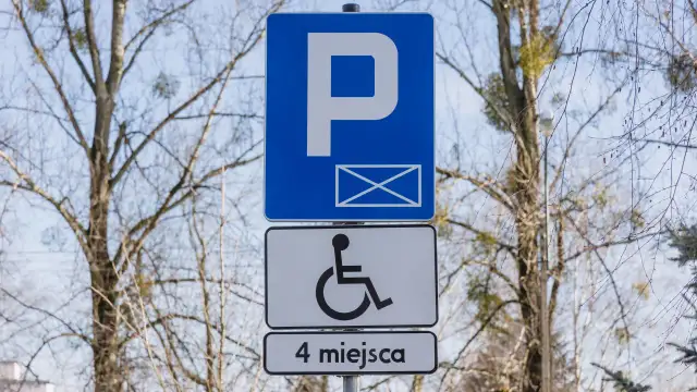 Znak P z kopertą i symbolem wózka inwalidzkiego, informujący o 4 miejscach parkingowych dla niepełnosprawnych.