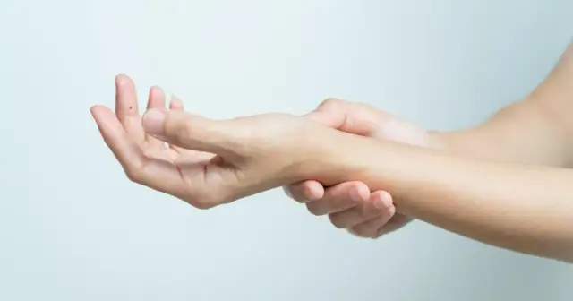 Dłoń delikatnie uciskana, sugerująca złamaną rękę bez gipsu.