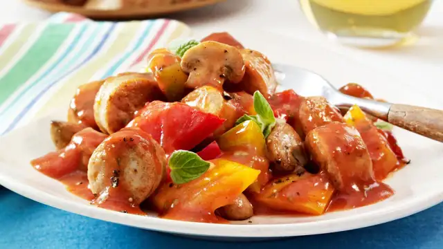 Herzhaftes Wurstgulasch mit Bratwurst, Tomaten und Pilzen, garniert mit frischen Kräutern. Ein deftiges Gericht für Genießer.