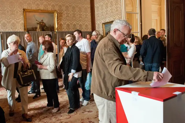 Ludzie w kolejce do głosowania. Dowiedz się, jak głosować za granicą, aby Twój głos miał znaczenie.
