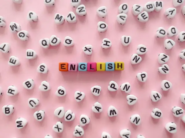 Kolorowe koraliki z literami tworzą napis "ENGLISH" na różowym tle.