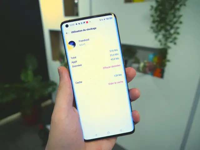 Une main tient un smartphone affichant l'option "Vider le cache" pour l'application Frandroid.