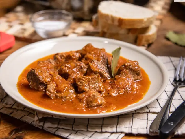 Sabrosa carne guisada con tomate, tiernos trozos de carne en una rica salsa, servida en un plato blanco.